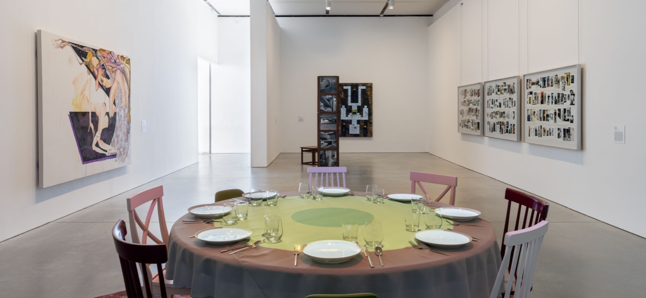 Gallery with round table setting and works on wall and sculptural works