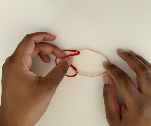 Folding a rubber band over another to create a knot