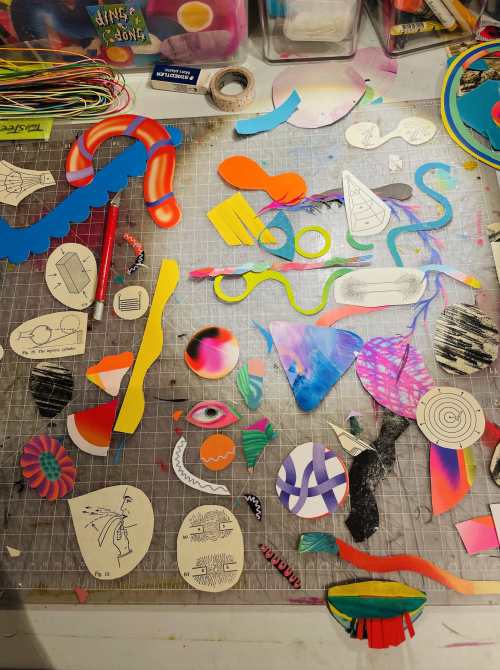 A studio shot of colorful cut out shapes on a desk