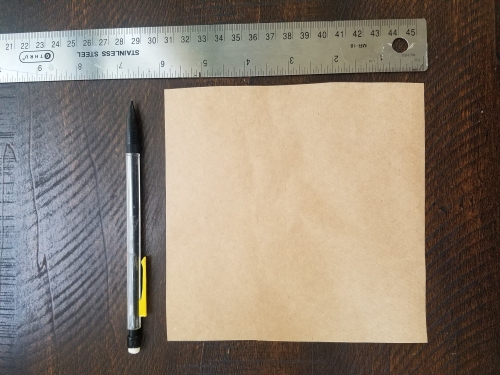 A 6 x 6 inch square piece of paper next to a ruler and pencil