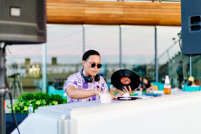 Photo of DJ behind DJ booth holding a vinyl record