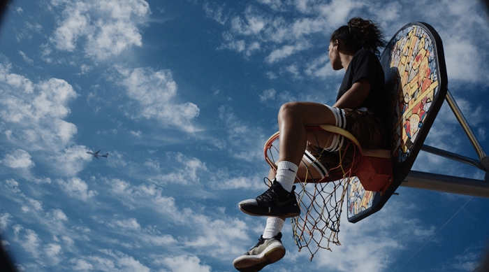 A guy sitting on top of a basketball hoop