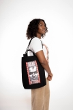 Person in casual clothing carries black tote bag with Barbara Kruger graphic