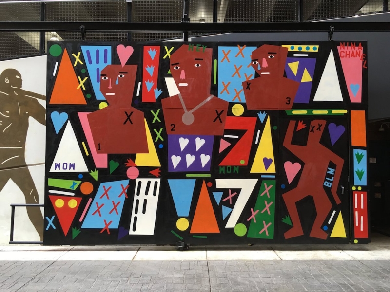 A wall-size work features colorful cutout figures, hearts, Xs, and other dynamic shapes.