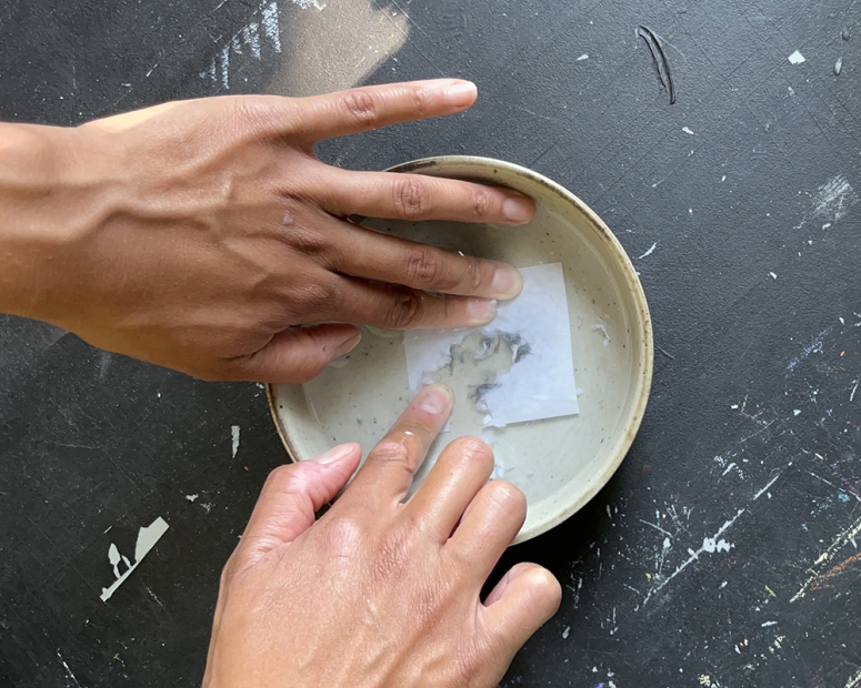 Hands rubbing a dissolving photo into a bowl