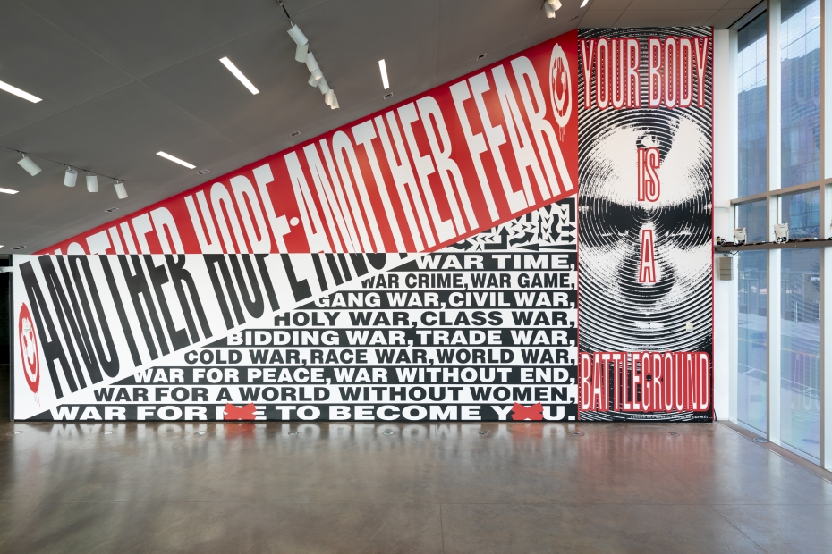 Wall art installation by Barbara Kruger featuring red, white, and black graphics and text