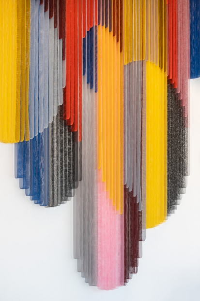 A close-up view of vibrant and colorful bands of coated mesh fabric hung and draped at various lengths.