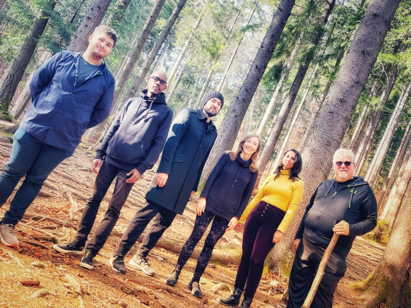 Photo taken at diagonal angle of six people standing in the woods
