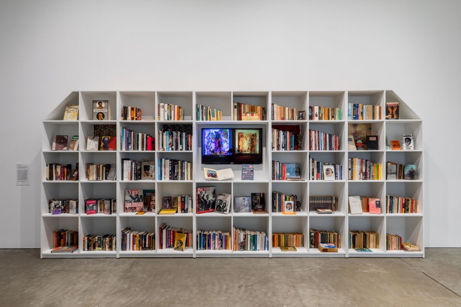 A large white shelving unit filled with books and memorabilia with a TV screen in the middle