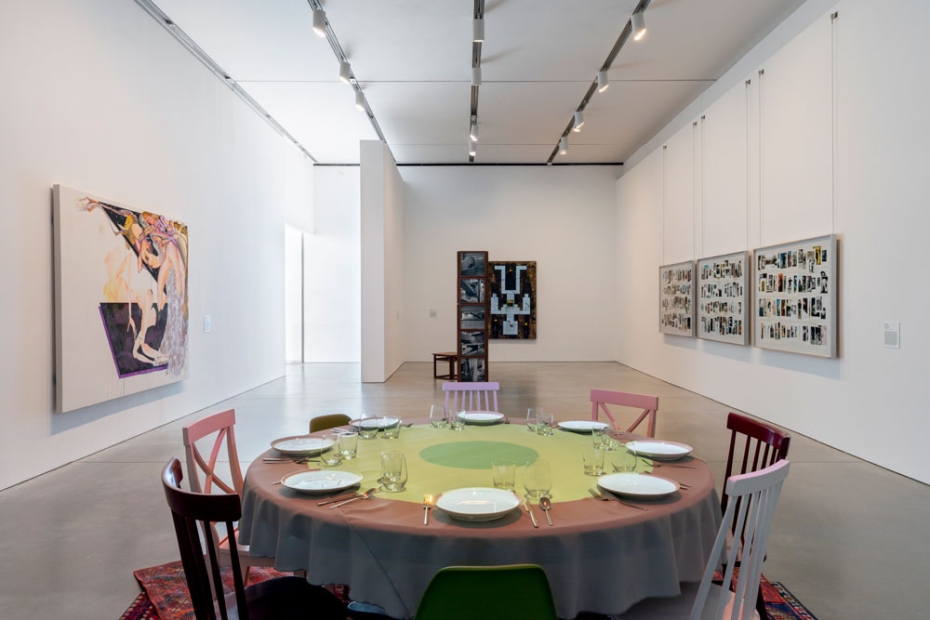 Gallery with round table setting and works on wall and sculptural works
