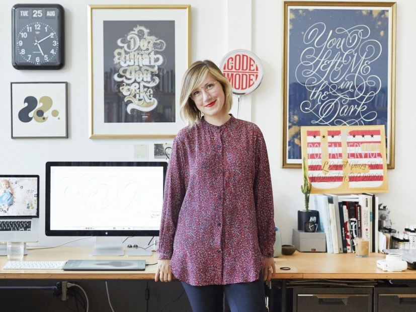 A blonde woman smiles surrounded by typography graphic posters