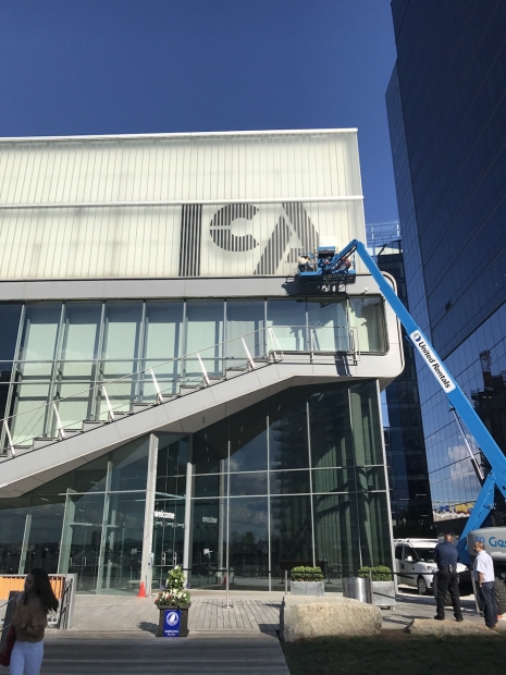People on a large crane install a new ICA logo on the museum building