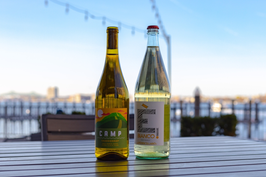 Two bottles of wine outside on a table facing the water