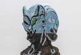 A bust by Huma Bhaba, that is gray and organic in texture, with the top covered in light blue paint. 