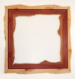 A flat wooden frame-like sculpture on the wall in the form of a roughly hewn square painted with concentric red geometric borders.