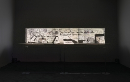 An installation shows a projection of a map with text that reads "bring enemy revolverr," "I assure you, we are not afraid. We are not sentimental," "annihilate," and "brutes" in all caps and in various parts of the map.