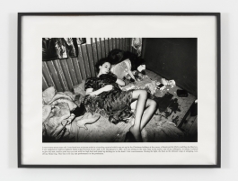 A black-and-white photograph of the artist lying on a messy floor with text under the picture.