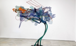 A large-scale, colorful sculpture of bronze and steel resembling a tree or flower.