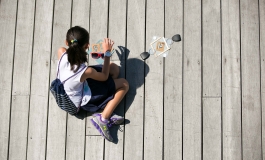 An elevated shot of a young child sitting on a wooden deck with art supplies