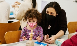 A mother and her child work together to work with clay