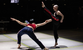A dancer bending backwards while another kicks above.