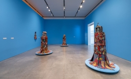 A blue gallery with three free-standing shrine-like sculptures