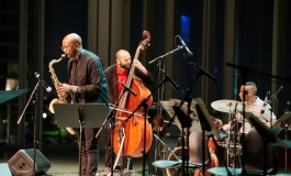 Musicians playing the saxophone, string bass, and drums on stage
