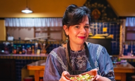 Chef Susana Trilling in a colorful kitchen holding a dish.