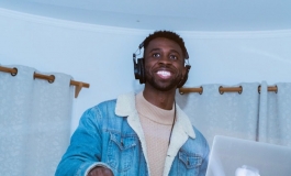 DJ SUNRAE smiling and wearing headphones .