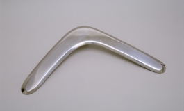 A sleek, polished, stainless-steel boomerang on a light background. 