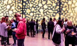 People drinking and hanging out in the ICA theater with yellow lights. 