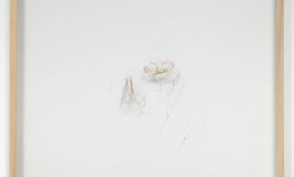 A sculpture of thin, wispy gold wire loosely shaped into two wedding ring shapes.
