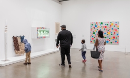 Two parents with 2 young children in view look at art inside the galleries