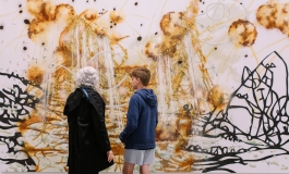 An elderly woman and a child look at a large painting with bold lines