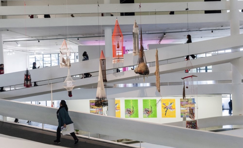 Objects handmade from fishing nets hang from the ceiling in an atrium with sloping floors