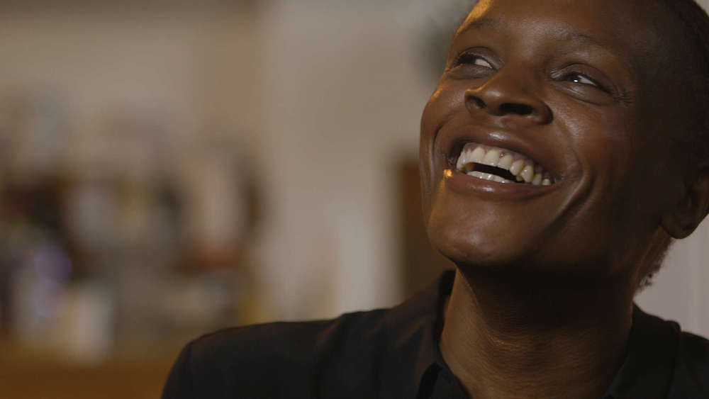 A film still shows an African American woman laughing.