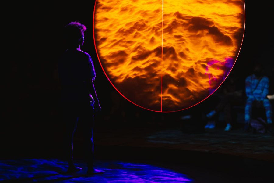 Person in low lighting looking into large circular screen showing orange ridges