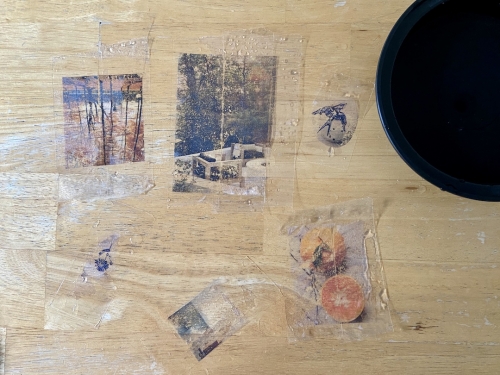 Various images and illustrations on clear tape, still slightly wet, after having been soaked in a bowl of water.