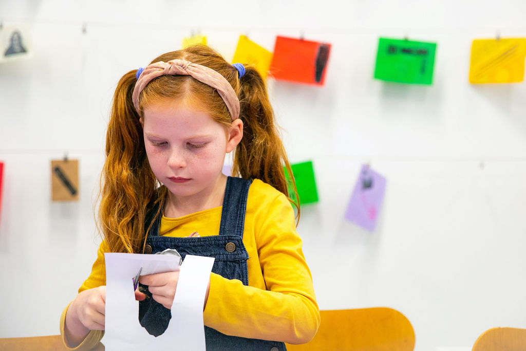 Child cutting a piece of paper at a table