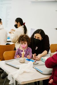 A mother and her child work together to work with clay