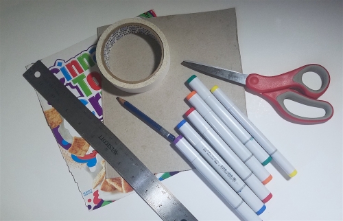 Scissors, markers, tape, a metal ruler, and the cut-out front and back of a cardboard cereal box.
