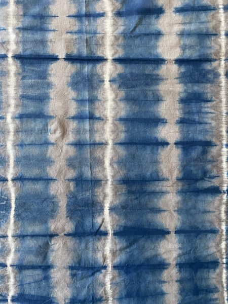 Light fabric with gridded, vibrating dyed design in a blue colored dye