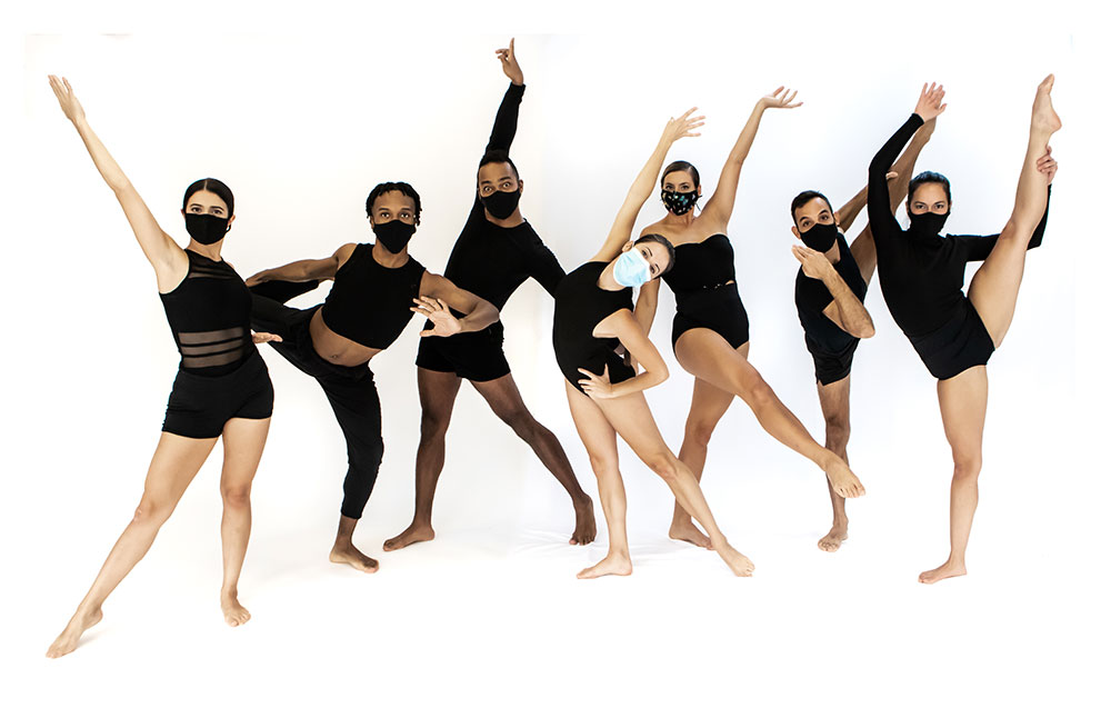 7 dancers in black leotards pose in front of a white background