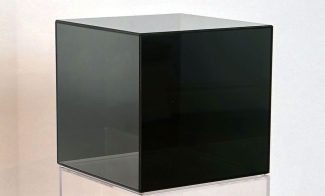 A sculpture of a glass cube covered in a black metallic coating.