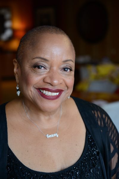 Woman with closely cropped hair and dark red lipstick smiling