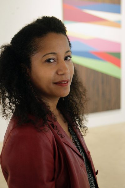 A woman in a red jacket in front of a painting. 