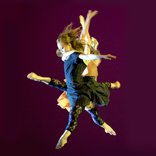 two dancers mid jump with one leg and both arms raised