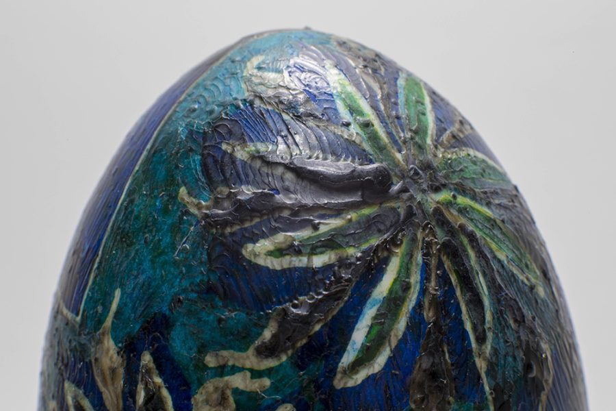 A close up photo of a decorated blue egg with flowers, showing the thick wax texture on the egg