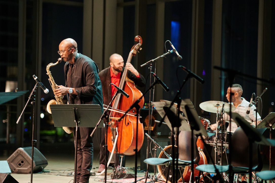 Musicians playing the saxophone, string bass, and drums on stage