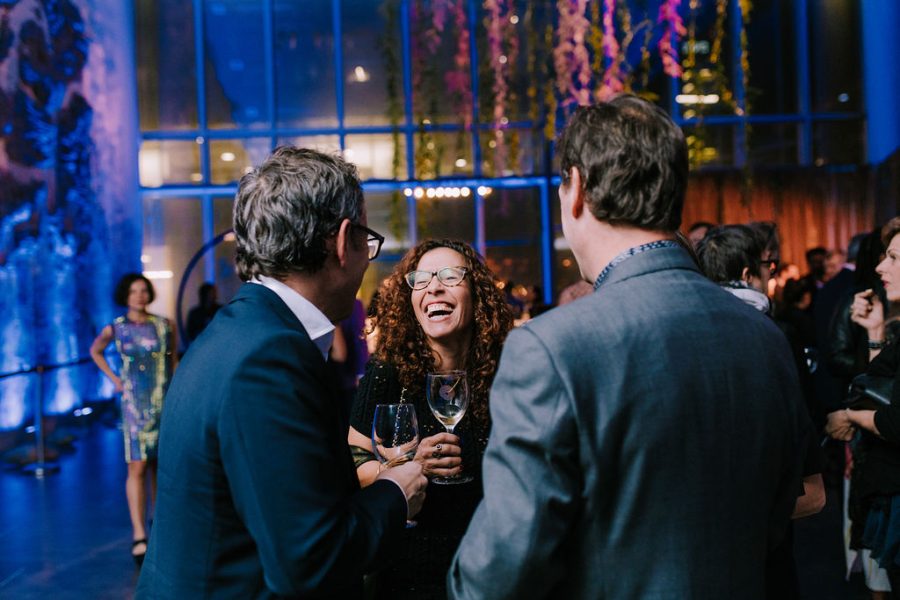 A group of people laughing and holding wine glasses in the ICA lobby